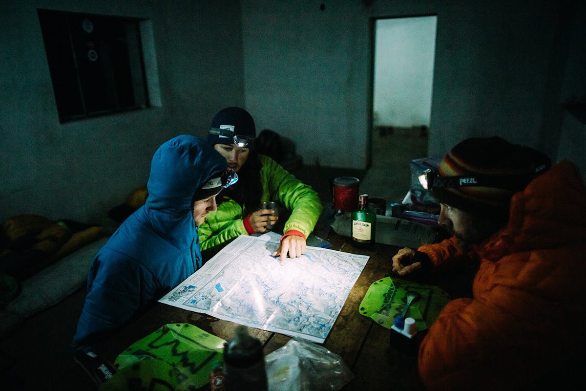 Thomas Woodson and Carston Oliver look over a topography map lit by headlamp. 