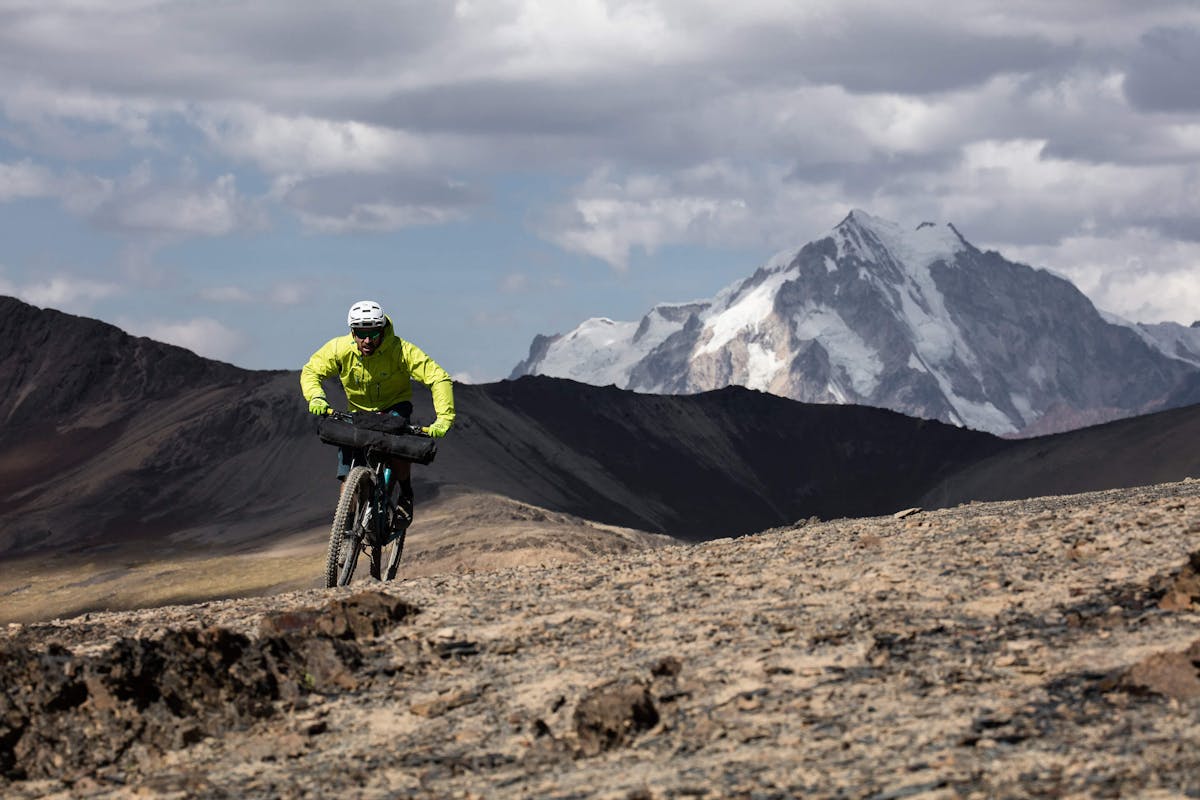 Nate Hills pedals single track on his Yeti SB5.5 with snow capped mountain peaks in the background