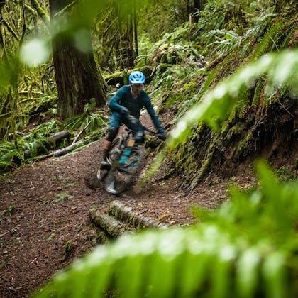 Geoff Kabush riding the SB100 in a lush forest.