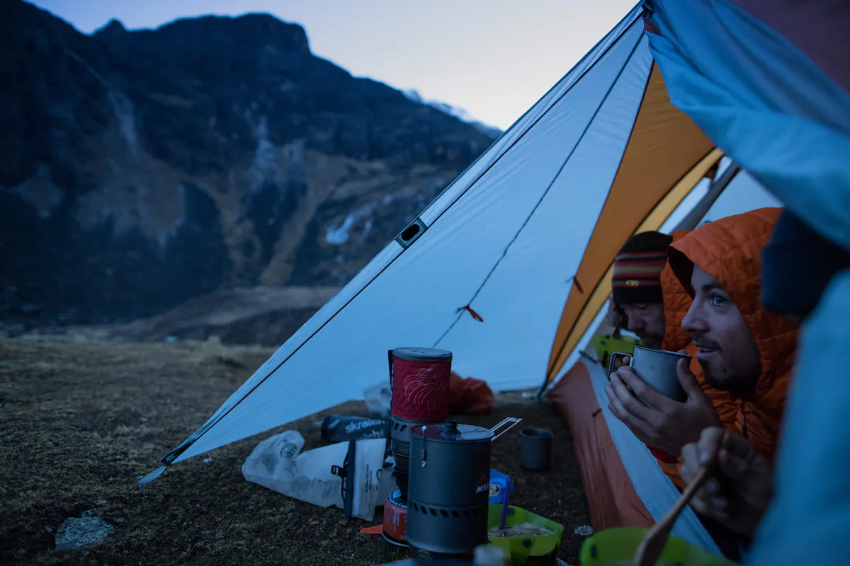 Thomas Woodson and Nate Hills sipping coffee in tent  at base camp