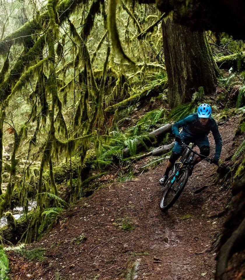 Geoff Kabush carving through a moss covered forest