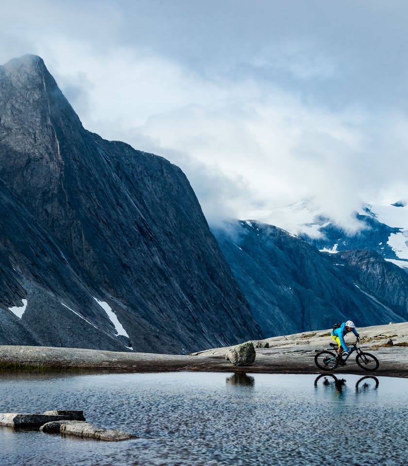 Joey Schusler on the edge of an apline lake with classic Norwegian mountains in the background.